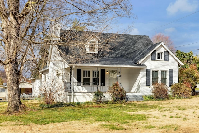 view of front of home featuring a front yard, covered porch, and roof with shingles