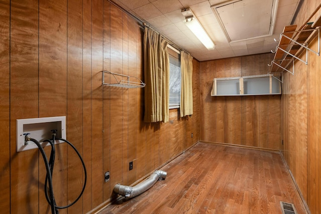 washroom with visible vents, wood finished floors, wood walls, hookup for a washing machine, and laundry area