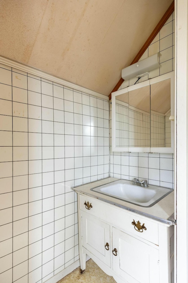 bathroom featuring vanity, vaulted ceiling, and tile walls