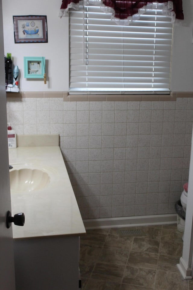 bathroom featuring tile patterned flooring, vanity, and tile walls