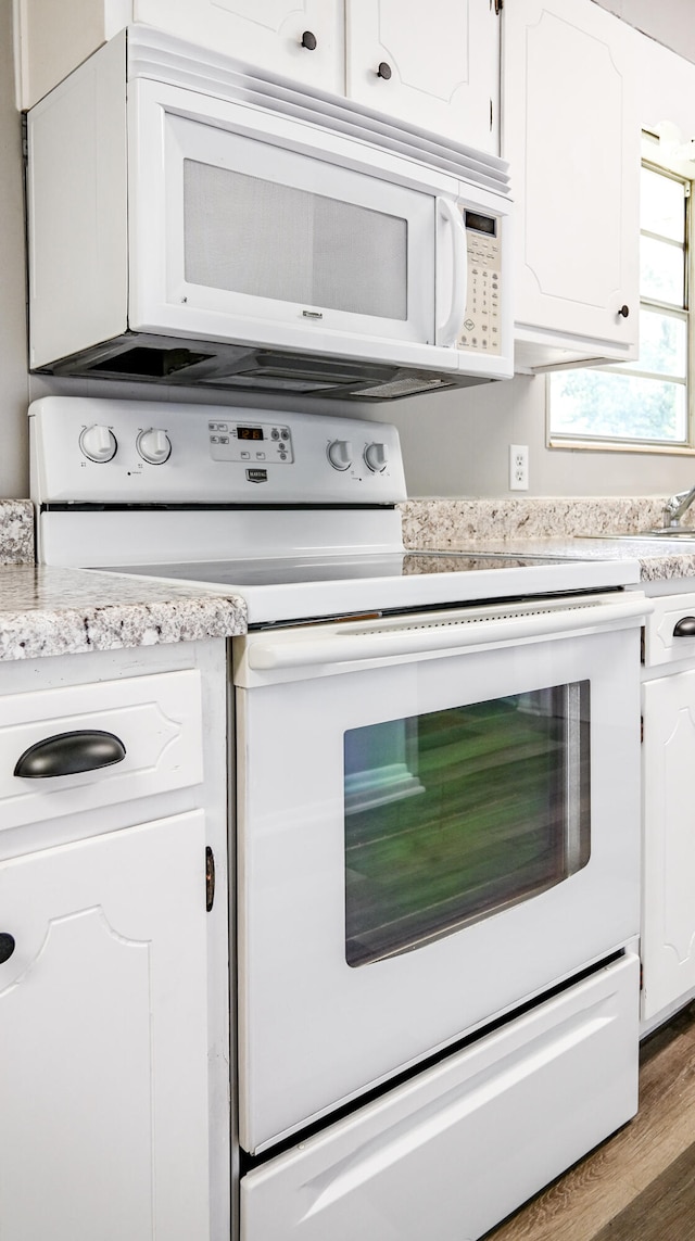 kitchen featuring white appliances, white cabinetry, and dark wood-type flooring