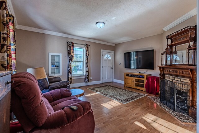 living room featuring hardwood / wood-style flooring, ornamental molding, a fireplace, and a textured ceiling