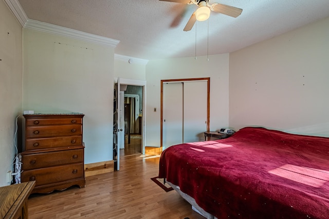 bedroom featuring light hardwood / wood-style flooring, ceiling fan, ornamental molding, a textured ceiling, and a closet