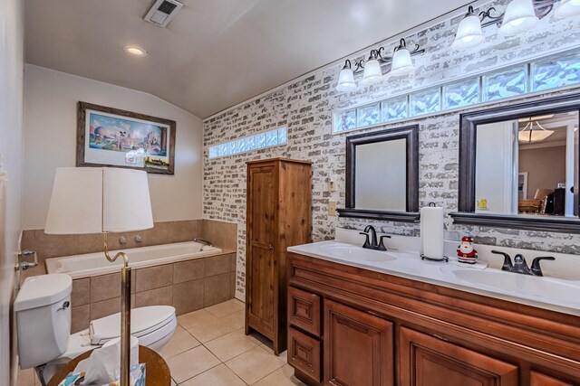 bathroom featuring vanity, lofted ceiling, tile patterned flooring, toilet, and tiled bath