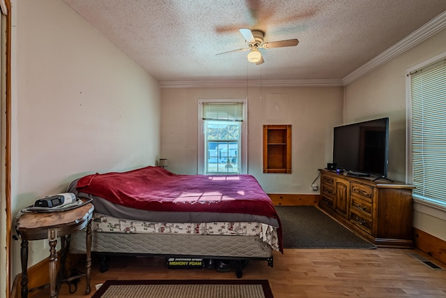 bedroom featuring hardwood / wood-style flooring, ceiling fan, ornamental molding, and a textured ceiling