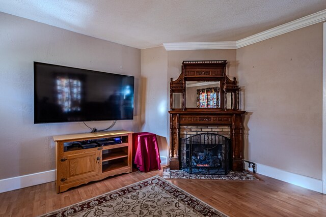 living room with hardwood / wood-style floors, crown molding, a brick fireplace, and a textured ceiling