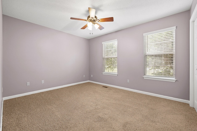 carpeted empty room featuring ceiling fan and a textured ceiling