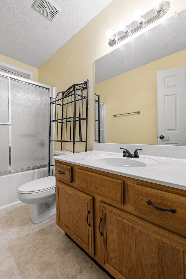 full bathroom featuring vanity, a textured ceiling, toilet, and shower / bath combination with glass door