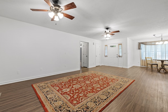 foyer entrance with ceiling fan with notable chandelier, a textured ceiling, and dark hardwood / wood-style floors