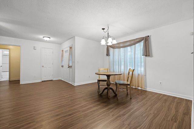 dining room featuring dark hardwood / wood-style flooring, a textured ceiling, and an inviting chandelier