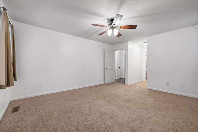 spare room featuring light carpet, ceiling fan, and a textured ceiling