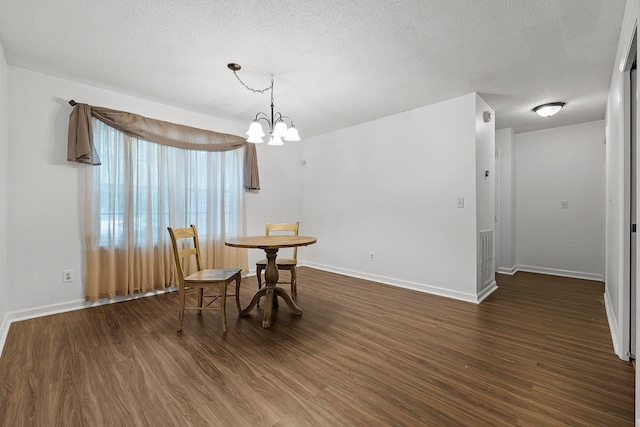 dining room with a textured ceiling, dark wood-type flooring, and a chandelier