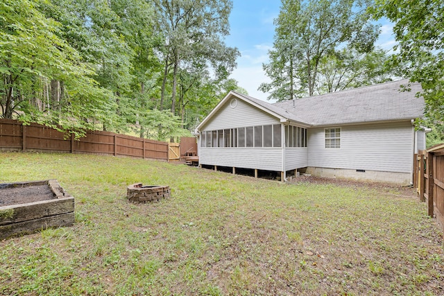 rear view of property with a sunroom, a yard, and an outdoor fire pit