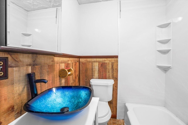 bathroom featuring a washtub, tile patterned floors, toilet, and sink