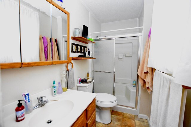 bathroom featuring vanity, crown molding, toilet, a textured ceiling, and a shower with shower door