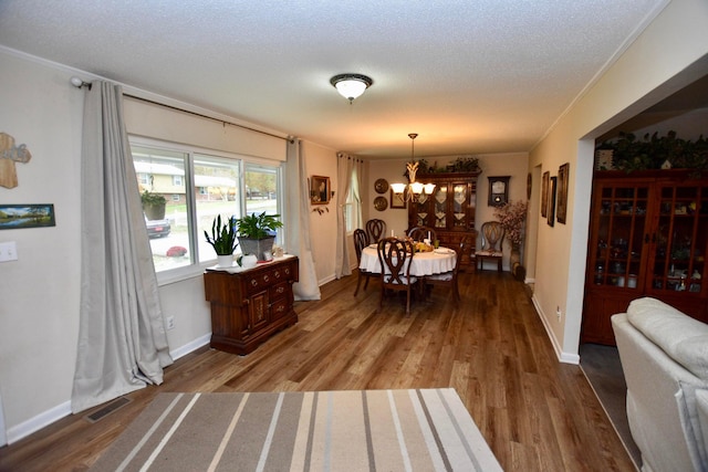 dining room with hardwood / wood-style floors, a notable chandelier, crown molding, and a textured ceiling