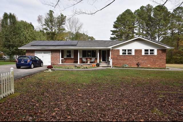 ranch-style home with solar panels, a porch, a garage, and a front yard