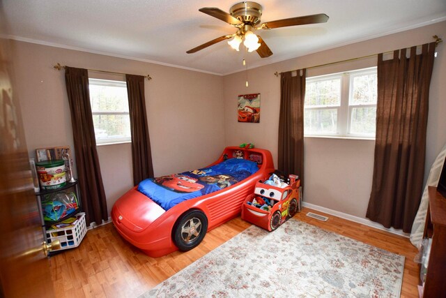 bedroom with hardwood / wood-style floors, ceiling fan, and crown molding