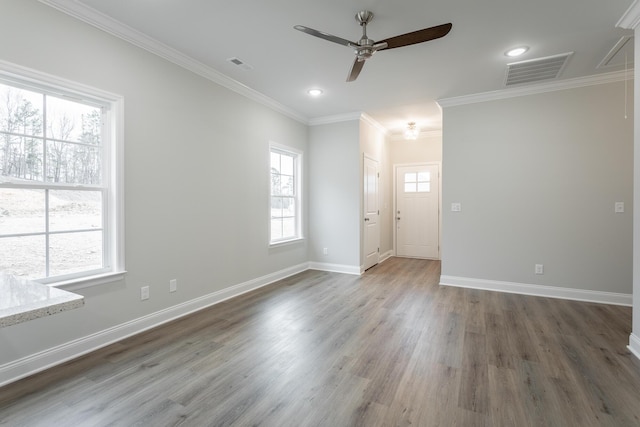 spare room featuring ornamental molding, a wealth of natural light, dark wood-type flooring, and ceiling fan