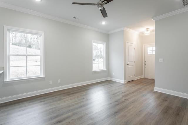 empty room featuring crown molding, ceiling fan, dark wood-type flooring, and a healthy amount of sunlight