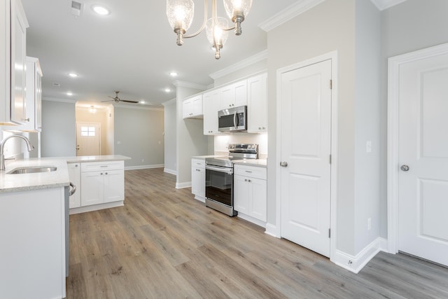 kitchen featuring white cabinetry, sink, stainless steel appliances, pendant lighting, and ceiling fan with notable chandelier