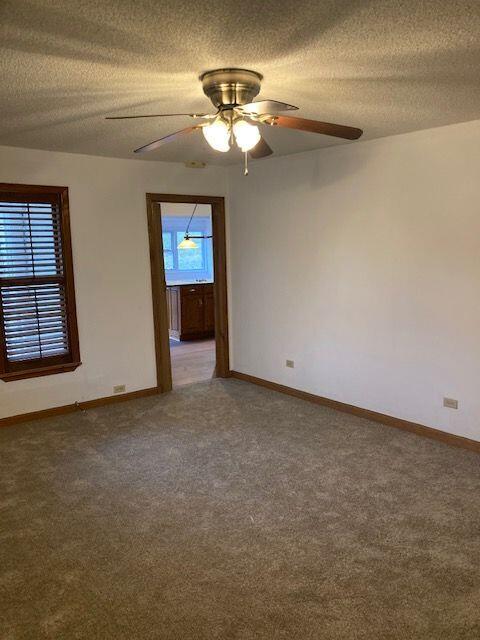 carpeted empty room featuring ceiling fan and a textured ceiling