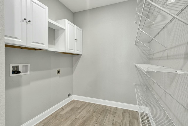 washroom featuring electric dryer hookup, hookup for a washing machine, light hardwood / wood-style floors, and cabinets