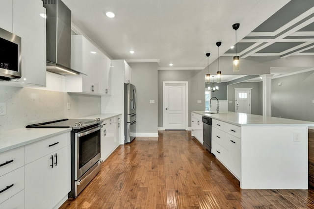 kitchen with wall chimney exhaust hood, stainless steel appliances, a kitchen island with sink, and white cabinets