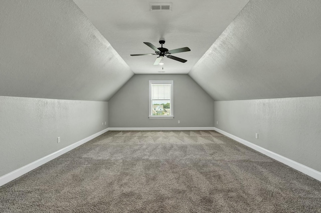 additional living space with ceiling fan, lofted ceiling, carpet flooring, and a textured ceiling