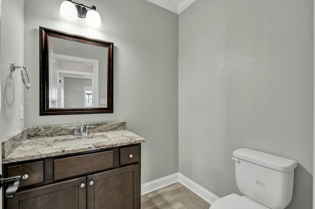 bathroom with vanity, wood-type flooring, crown molding, and toilet