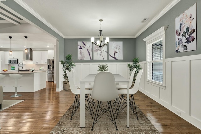 dining room with crown molding, sink, a notable chandelier, and dark hardwood / wood-style flooring