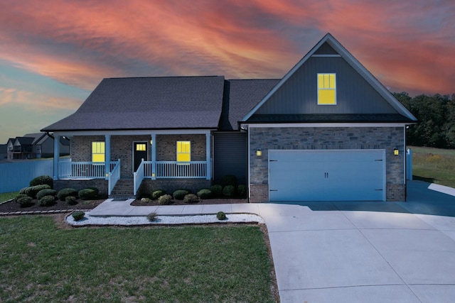 view of front of property with a garage, a lawn, and a porch