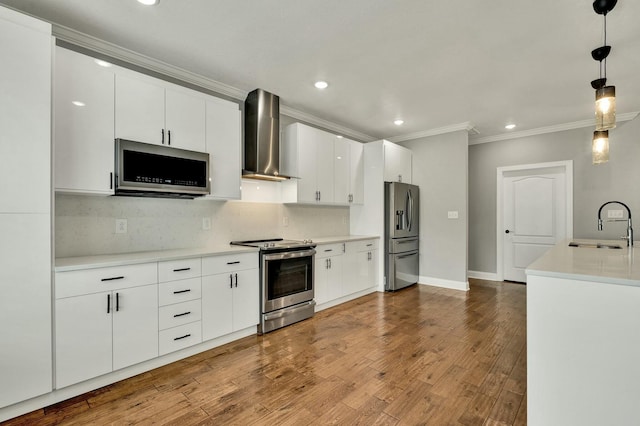 kitchen featuring pendant lighting, sink, white cabinets, stainless steel appliances, and wall chimney exhaust hood