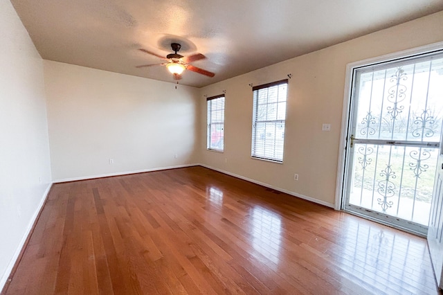 spare room with baseboards, wood-type flooring, and ceiling fan