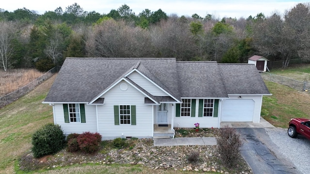 ranch-style home featuring aphalt driveway, an attached garage, a shingled roof, and fence