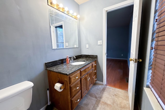 bathroom with toilet, vanity, and baseboards