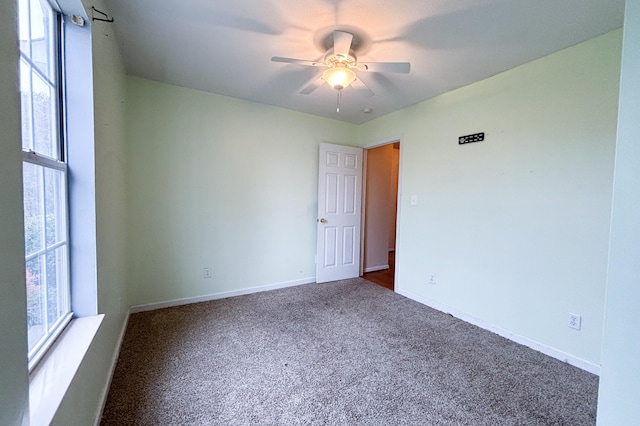 carpeted spare room featuring baseboards and ceiling fan