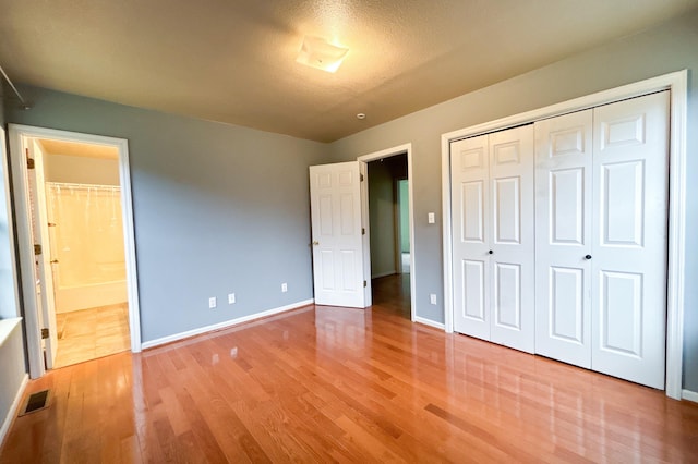 unfurnished bedroom with a closet, light wood-style flooring, connected bathroom, and baseboards