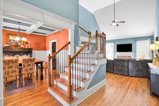 staircase with beam ceiling, coffered ceiling, hardwood / wood-style floors, and ceiling fan with notable chandelier