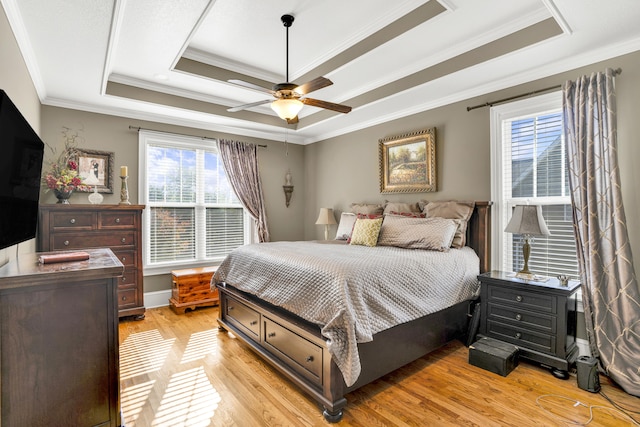 bedroom featuring ceiling fan, light hardwood / wood-style floors, a raised ceiling, and crown molding