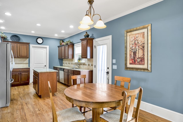 dining space featuring a chandelier, light hardwood / wood-style flooring, ornamental molding, and sink