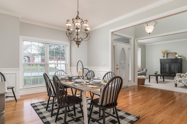 dining space with ornamental molding, light hardwood / wood-style flooring, and a chandelier