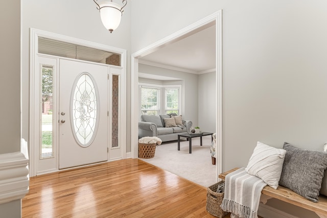 entrance foyer with light hardwood / wood-style floors and crown molding