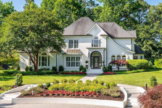 view of front of house featuring a shingled roof, stucco siding, and a front lawn