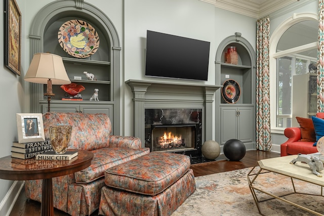 sitting room featuring built in features, ornamental molding, wood finished floors, and a high end fireplace