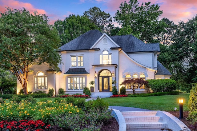 view of front of home with french doors, roof with shingles, and a front lawn
