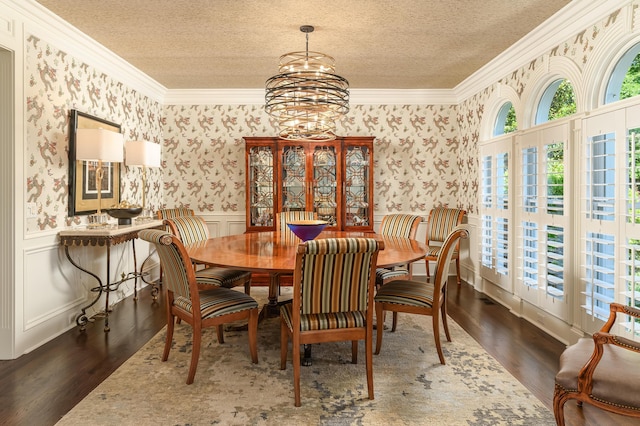 dining room with a textured ceiling, wallpapered walls, and wood finished floors