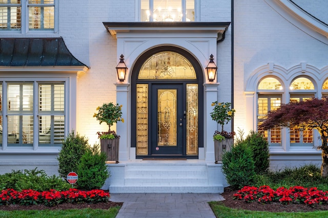entrance to property featuring brick siding, covered porch, and a standing seam roof