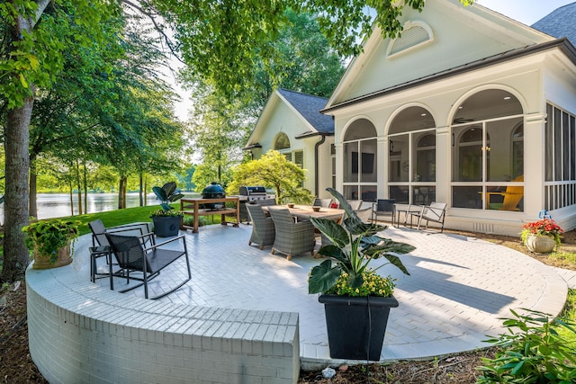 view of patio / terrace with a water view, outdoor dining space, and a sunroom
