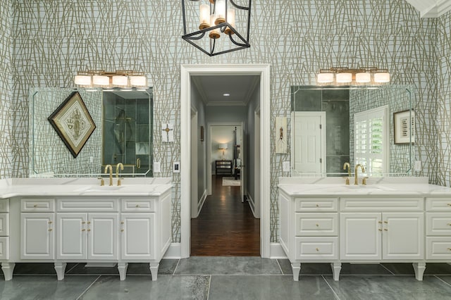 bathroom with crown molding, a sink, a chandelier, baseboards, and wallpapered walls